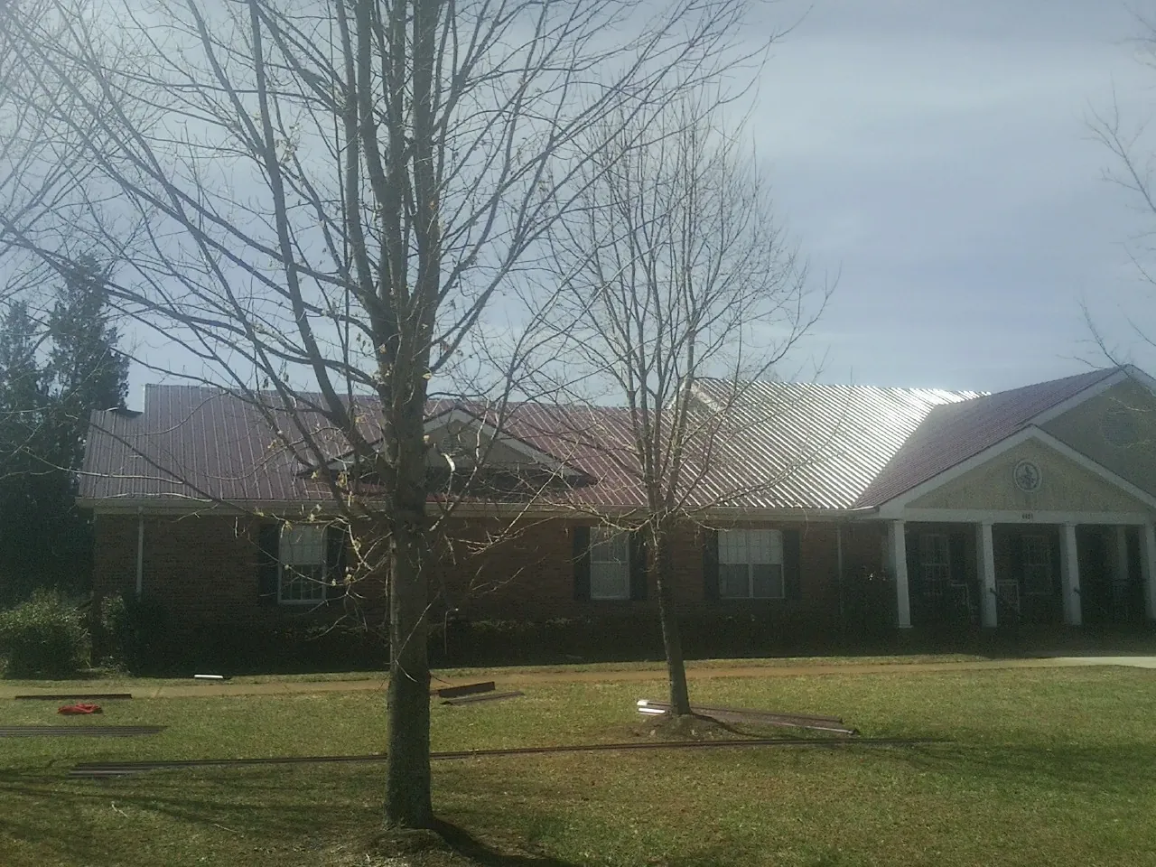 Red metal roof on a brick building seen from the front lawn in Crystal Springs
