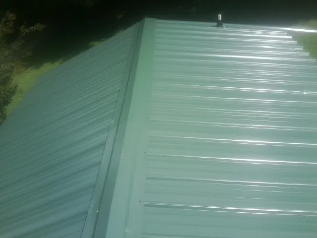 New green metal panels meeting at the ridge of a roof — Flat Roof Repair work by our crew in Crystal Springs