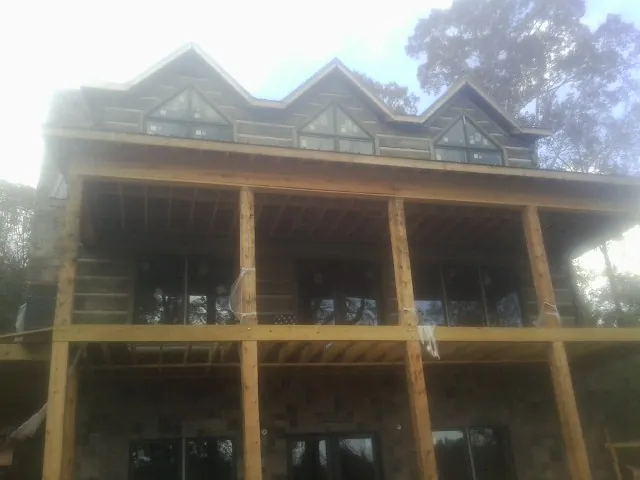 Dormers and porch framing on a large log home under construction — Roof Coating work by our crew in Crystal Springs