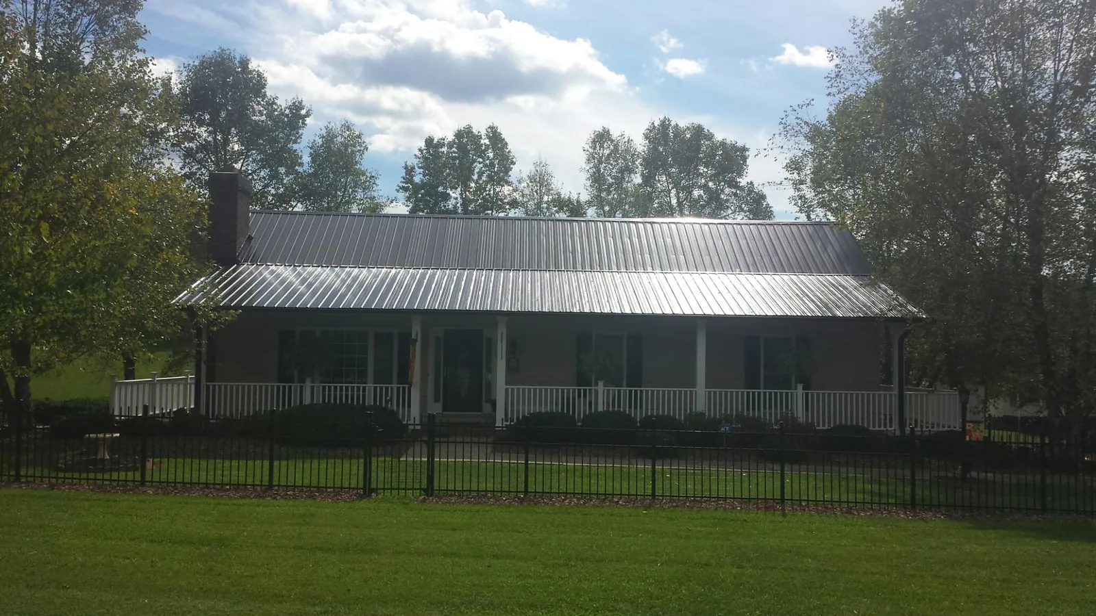 Gray metal roof on a brick ranch with a full width front porch — Gutter Guard Installation work by our crew in Crystal Springs