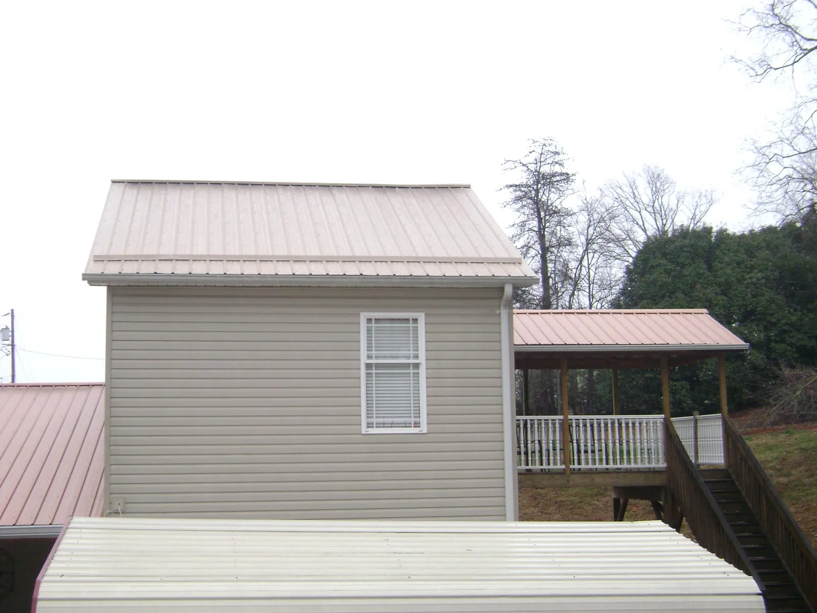 Tan metal roofs on a two story addition and attached porch, from a Roof Replacement job in Crystal Springs