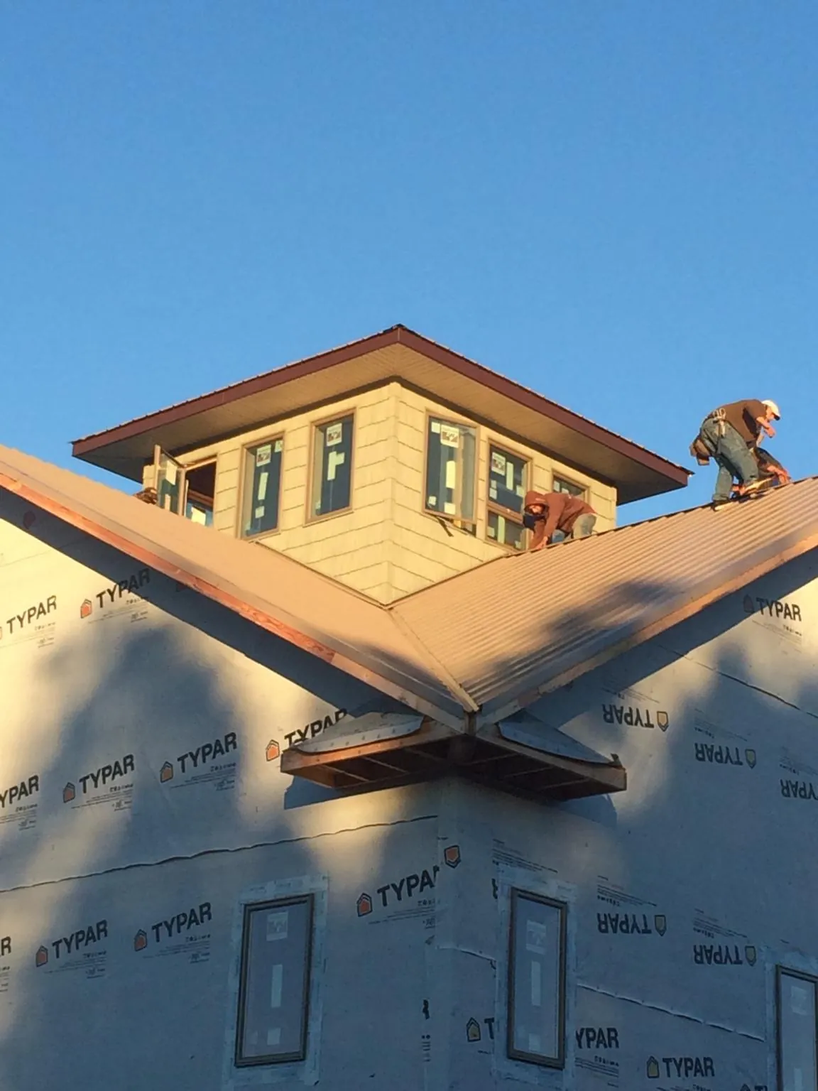 Roofers working around a rooftop cupola on a new metal roof at sunset — Roof Waterproofing in Crystal Springs by Roofing Brothers